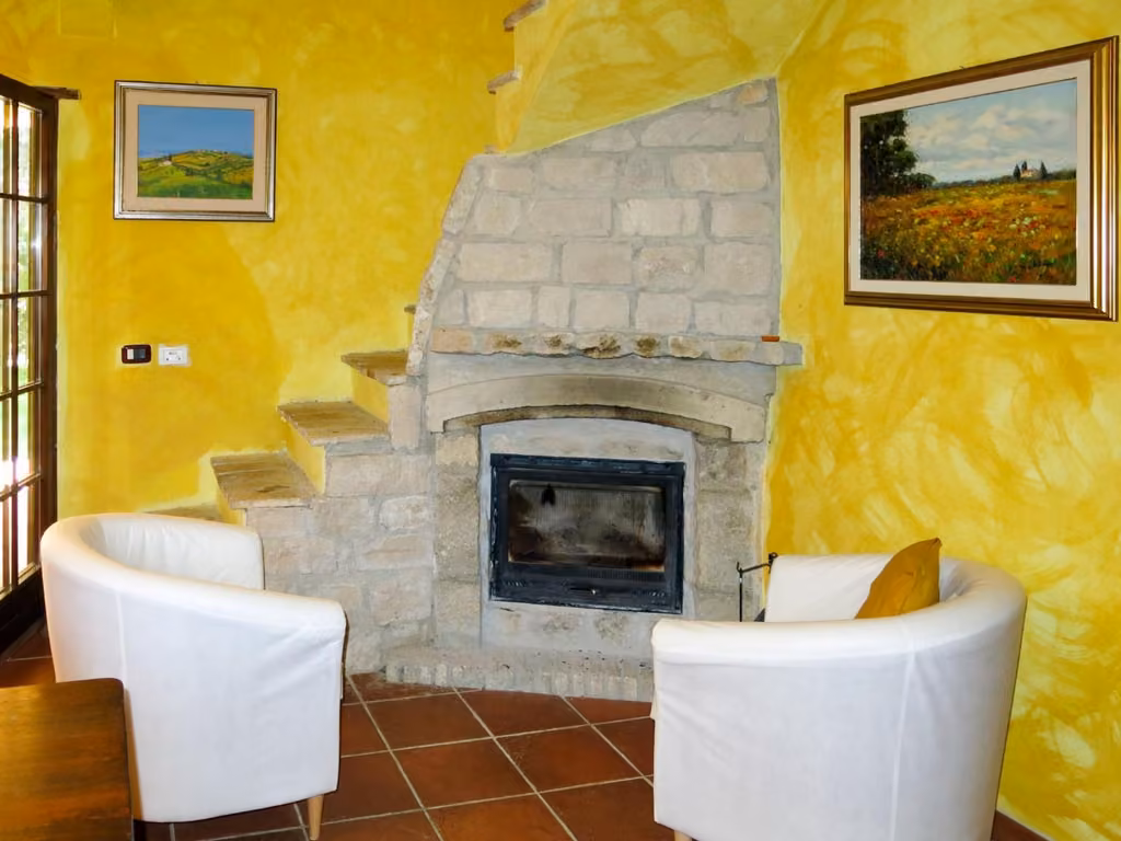 Il soggiorno dell'Agriturismo Casale Vidorni con il camino in pietra e le sedie bianche