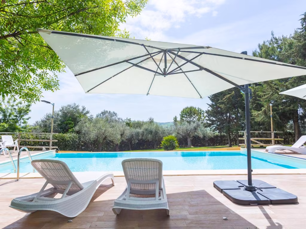 La piscina dell'agriturismo con due sedie e un ombrellone